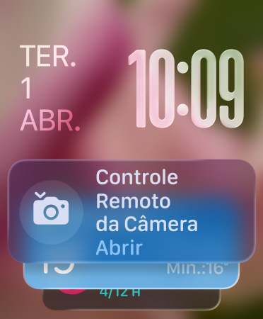 O widget Controle Remoto da Câmera aparece na parte inferior da tela, números das horas translúcidos no canto superior direito e data no canto superior esquerdo..