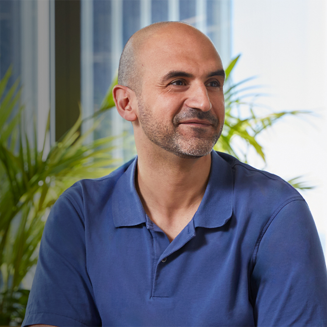 Ahmed istuu sisätiloissa, hymyilee ja katsoo ohi kameran vasemmalle.