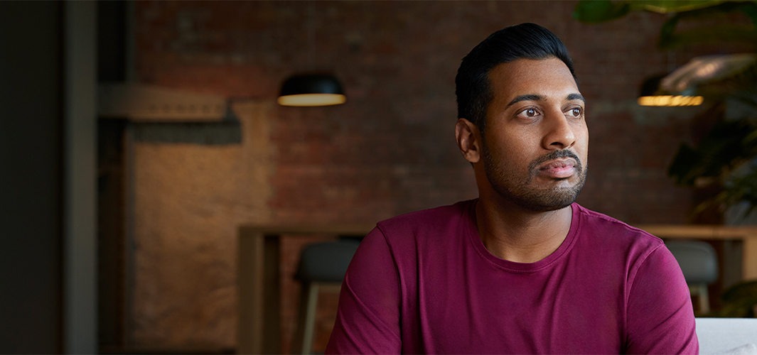 Amar istuu sisätiloissa ja katsoo vasemmalle puolelleen.