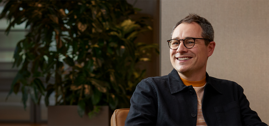 Dan hymyilee, istuu nojatuolissa ja katsoo jotakuta oikealla puolellaan.