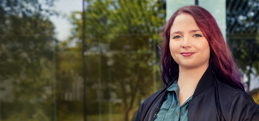 Alexa seisoo ulkona katsoen kohti kameraa.