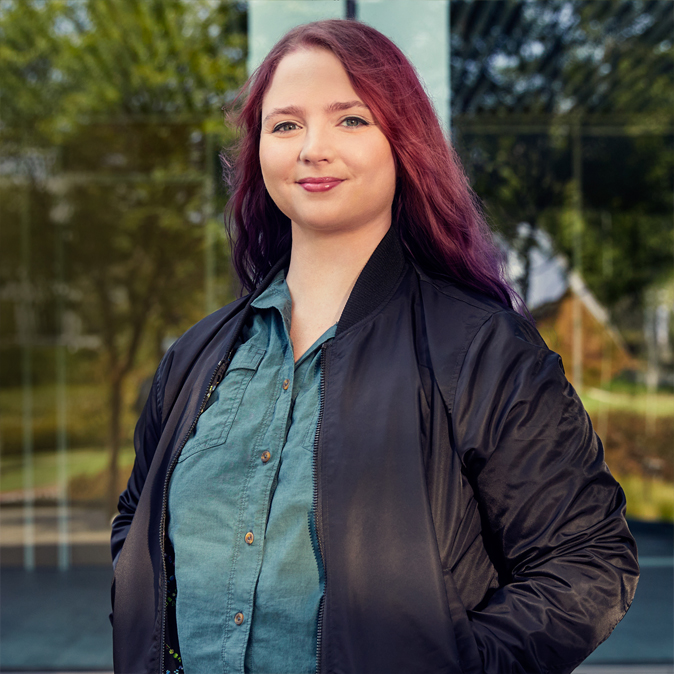 Alexa seisoo ulkona katsoen kohti kameraa.