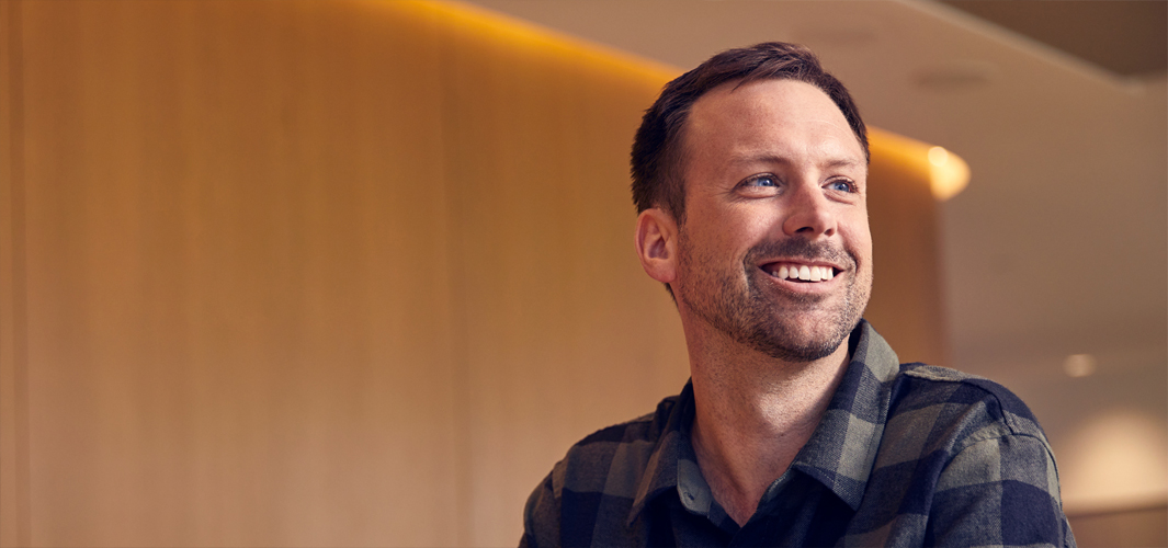 Jordan istuu ja hymyilee. Hän on on laittanut kädet ristiin eteensä.