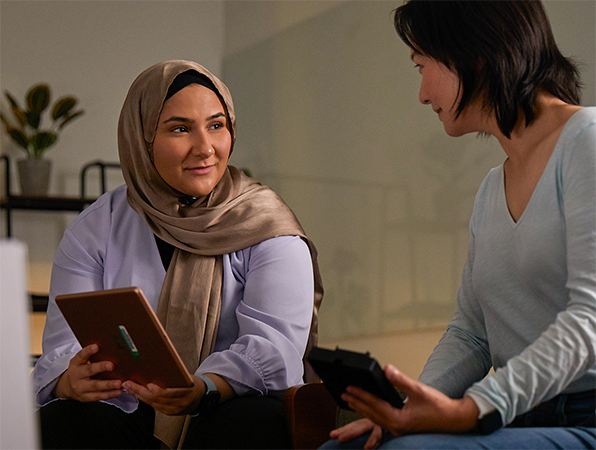 Two Apple Machine Learning and AI team members collaborating together, one holding an iPad and one holding an iPhone.
