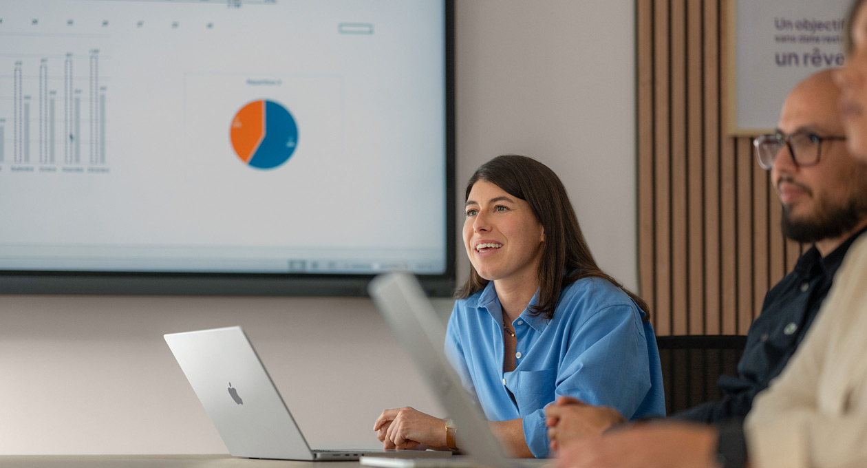 Funcionários numa reunião a utilizar computadores MacBook