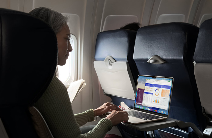 Una persona seduta in aereo che lavora su un MacBook Air