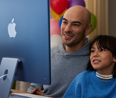 Adult and young child both engaged in content on iMac, blue