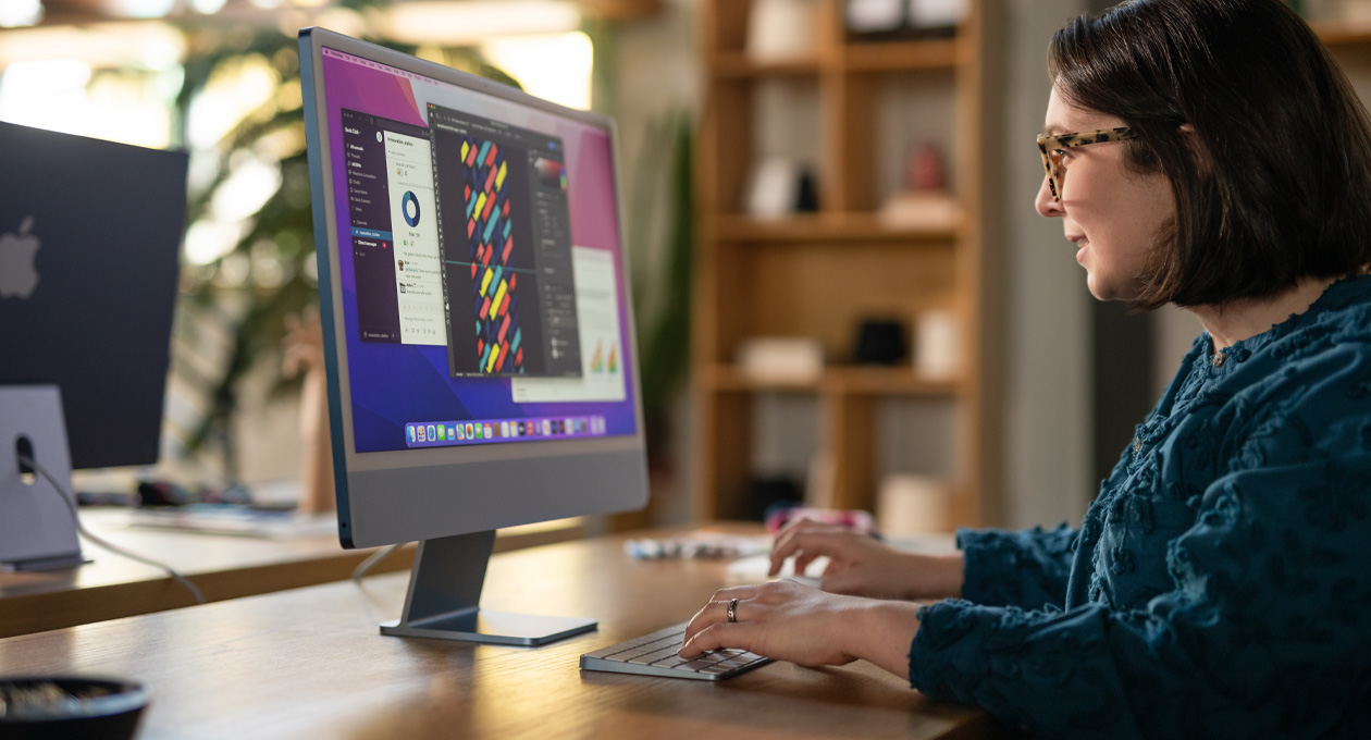 A person works at an iMac displaying a colourful design app in an office setting