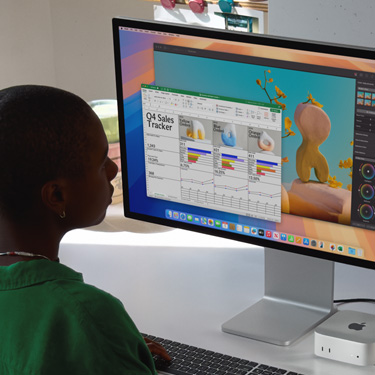 Une femme assise à un bureau travaille dans Excel sur Mac. La feuille de calcul fait le suivi des ventes du quatrième trimestre. En arrière-plan, une fenêtre Pixelmator Pro est ouverte.