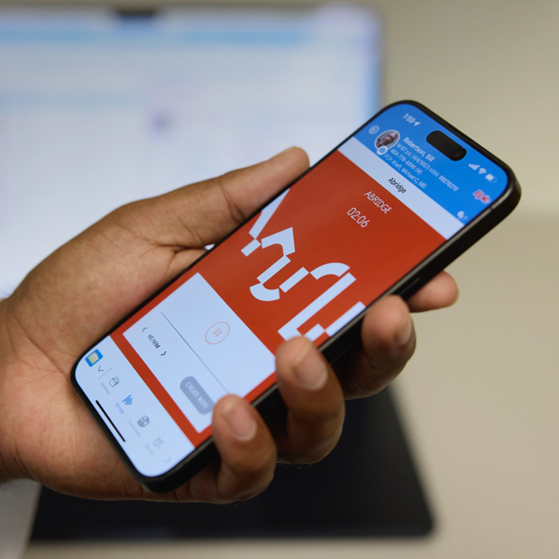 En hånd holder en iPhone, som viser Abridge-appen, der omsætter patientsamtaler til noter.