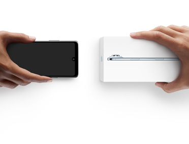 Hände tauschen Smartphones, links ist ein Android ohne Verpackung, rechts ist ein neues iPhone Air im Karton
