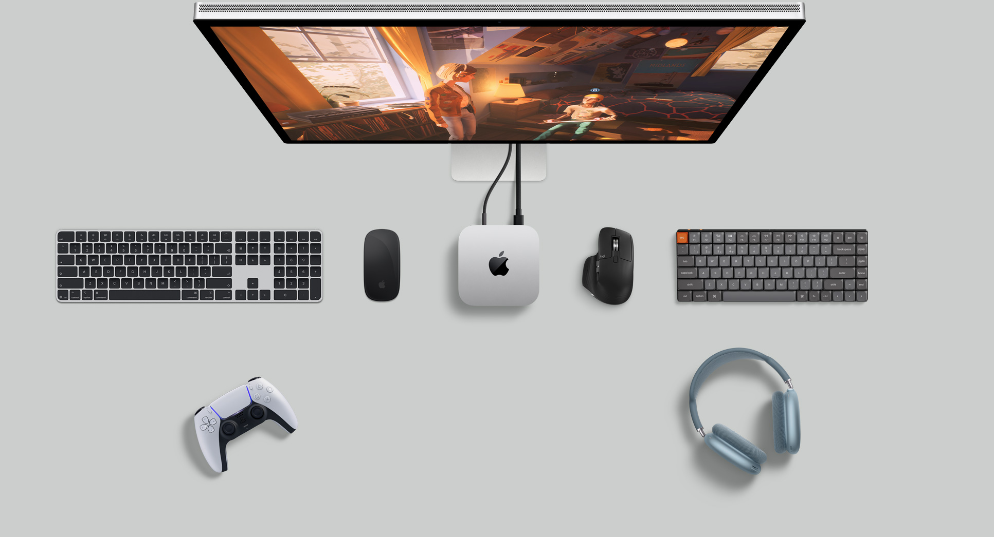Top view of Mac mini in a desk setup with Studio Display, wireless keyboards, wireless mice, a gaming controller, and AirPods Max
