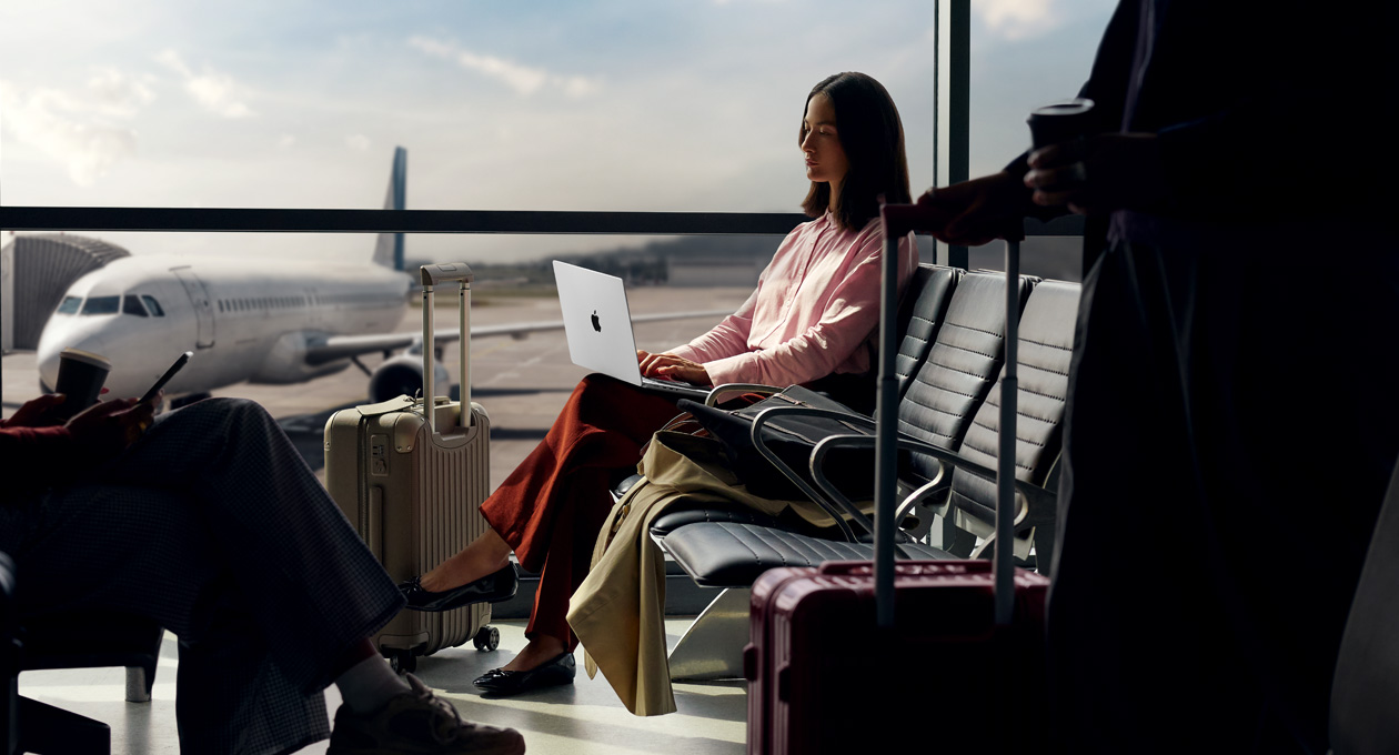 Eine Person in einem Flughafen nutzt ihr MacBook Pro