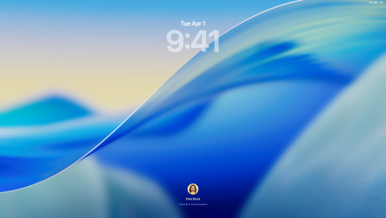 Tři modely Macu orientované obrazovkami dopředu, vlevo stříbrný 16palcový MacBook Pro s otevřenou aplikací Telefon, ve které jsou vidět poslední kontakty, uprostřed modrý 24palcový iMac s tapetou macOS Tahoe na obrazovce, vpravo temně inkoustový 13palcový MacBook Air, na obrazovce je hledání Spotlight nad plochou s Liquid Glass verzí Docku a různými widgety, například Kalendářem, Hodinami a Počasím