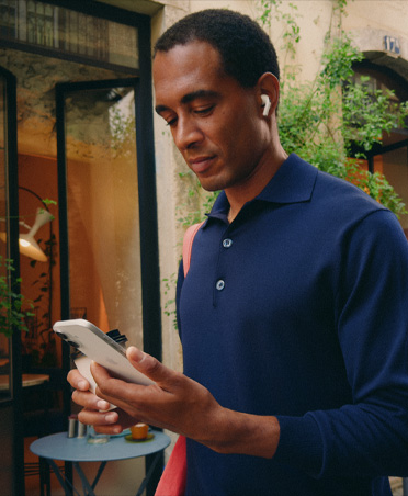 Person on a city street looking at their iPhone, maintaining seamless Wi‑Fi connection across network transfers