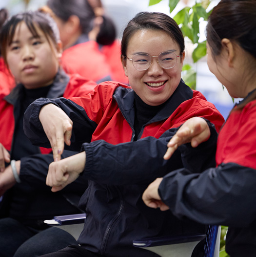 Three employees sit together as one signs to another